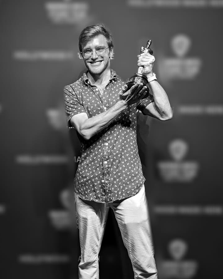 Jordan holding a prop statuette in front of a Hollywood studio-tour backdrop.
