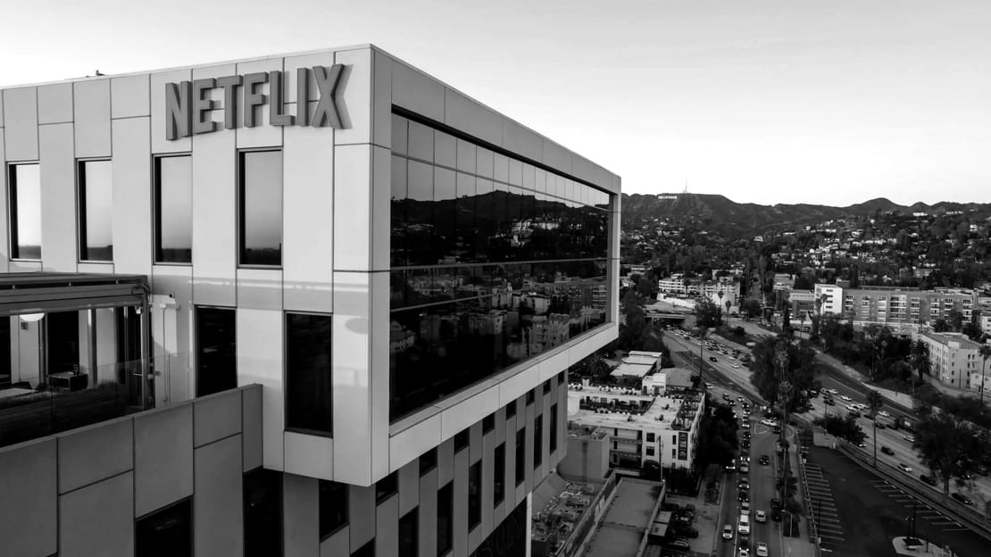 Netflix’s office building in Hollywood at sunset, in black and white, with the Hollywood sign on the hills behind it.