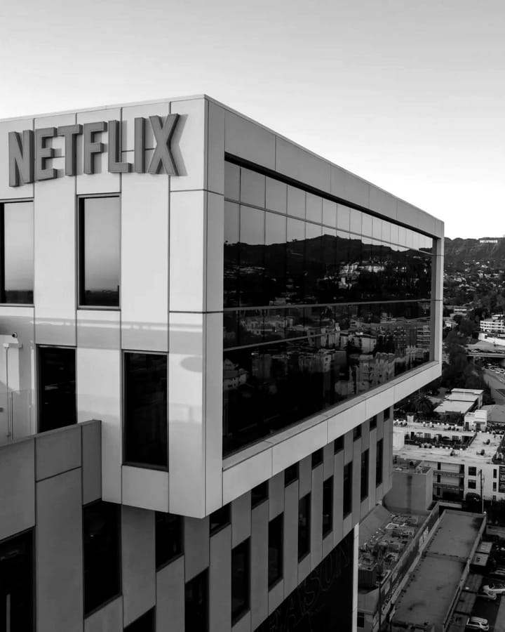 Netflix’s office building in Hollywood at sunset, in black and white, with the Hollywood sign on the hills behind it.